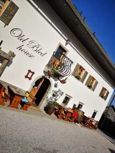 White Old Bled House exterior with outdoor wooden tables under a clear blue sky.