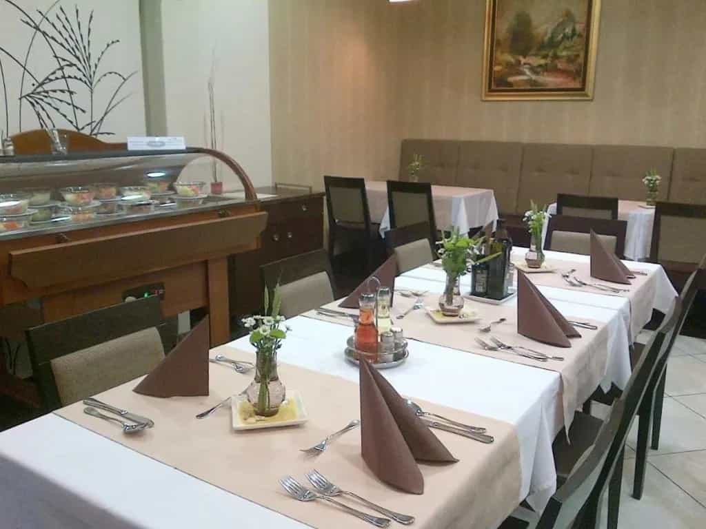 Dining room set for breakfast with a salad bar display and mountain painting.