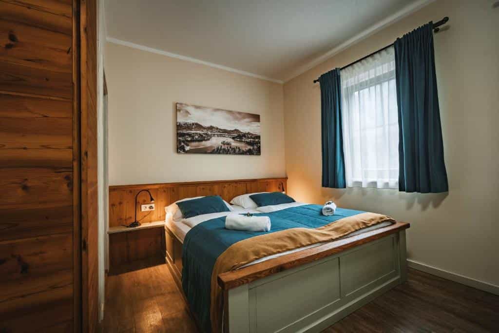 Bedroom with wooden bed frame, blue bedding, and mountain artwork above the headboard