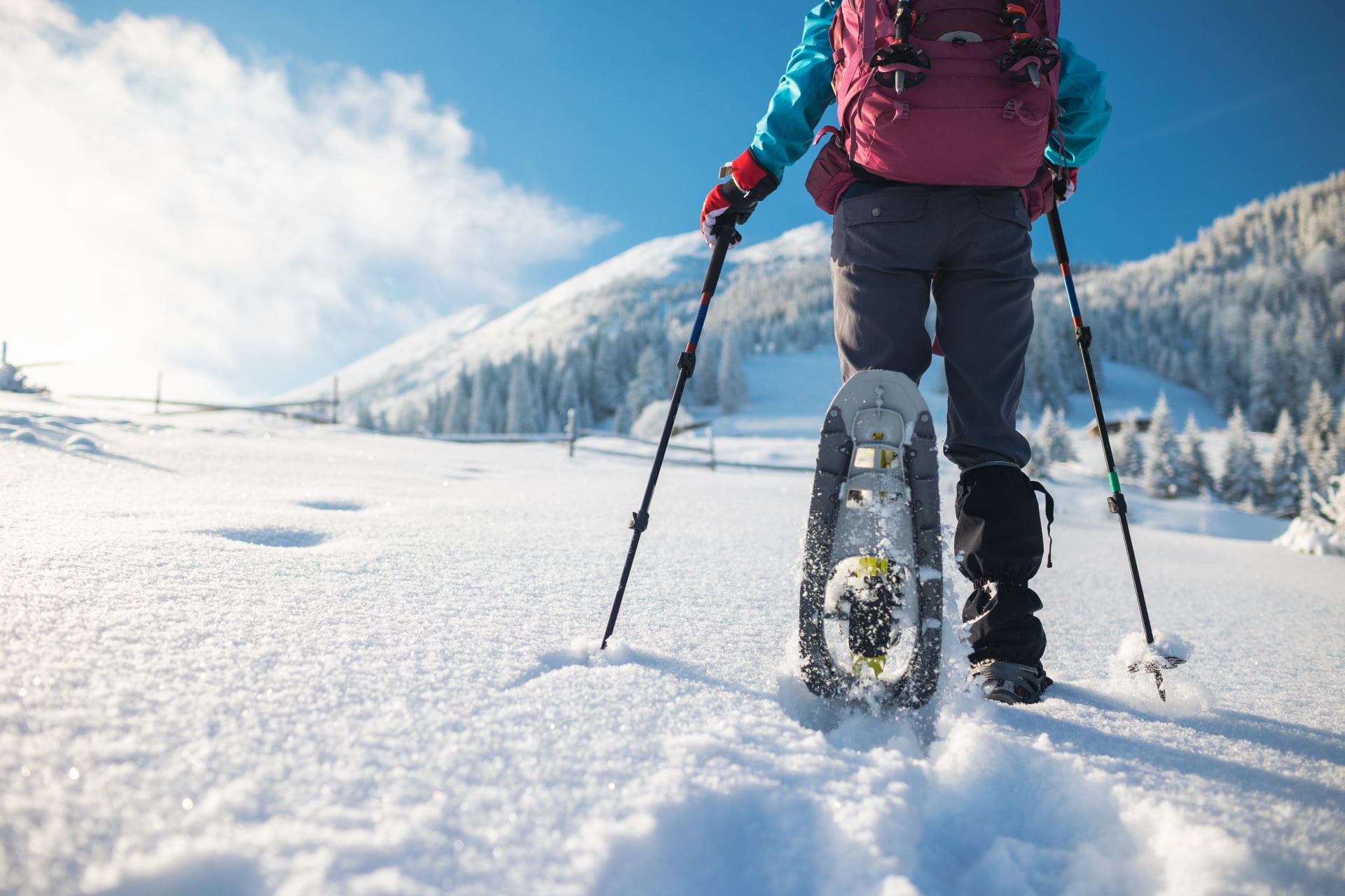 Eine Frau mit einem Rucksack in Schneeschuhen erklimmt einen schneebedeckten Berg