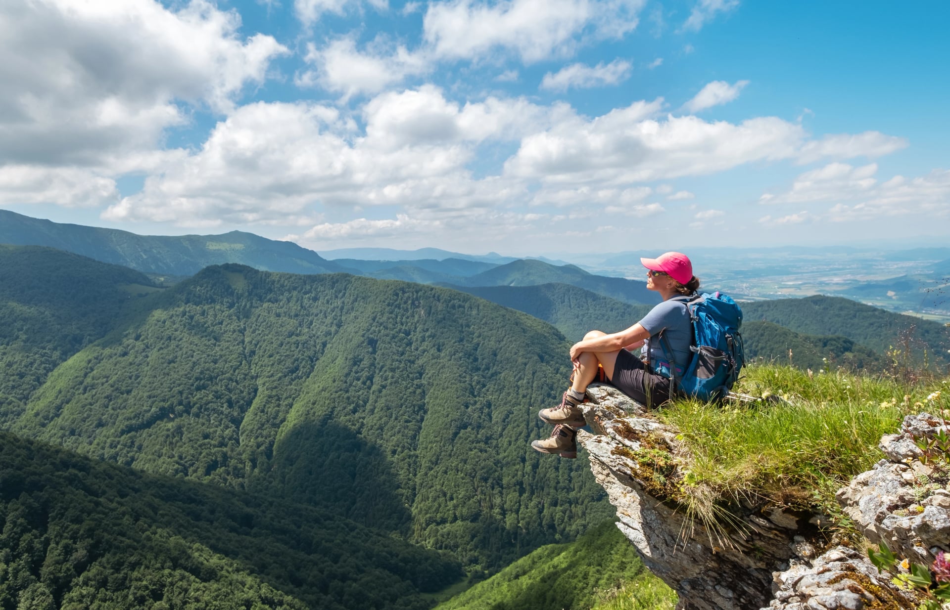 Frau in Trekkingkleidung sitzt auf einer felsigen Klippe und genießt das grüne Tal im Mala Fatra Gebirgen, Slowakei. Aktive Menschen und europäisches Tourismus-Konzeptbild.