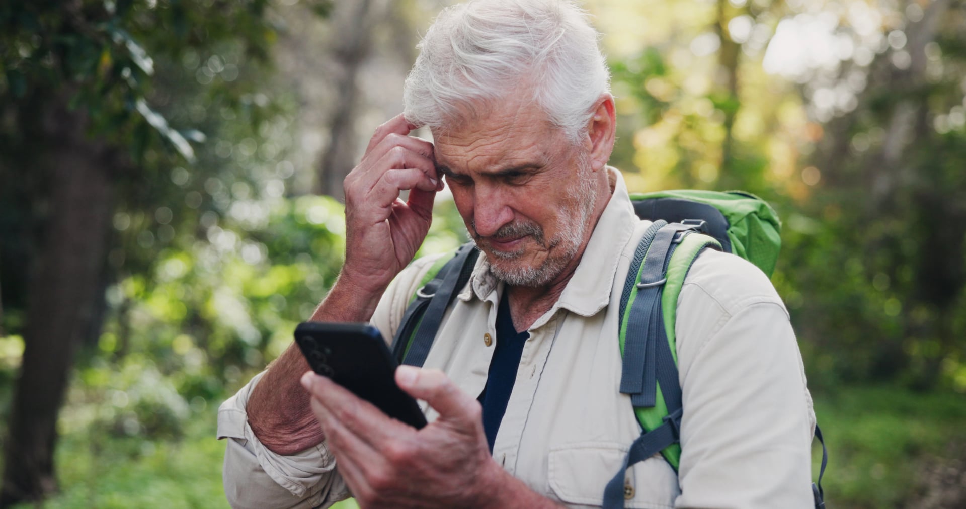 Thinking, phone and mature man in nature for directions, navigation app and checking route. Lost, low signal and ecologist in woods with mobile, connectivity and location tracking error in wilderness