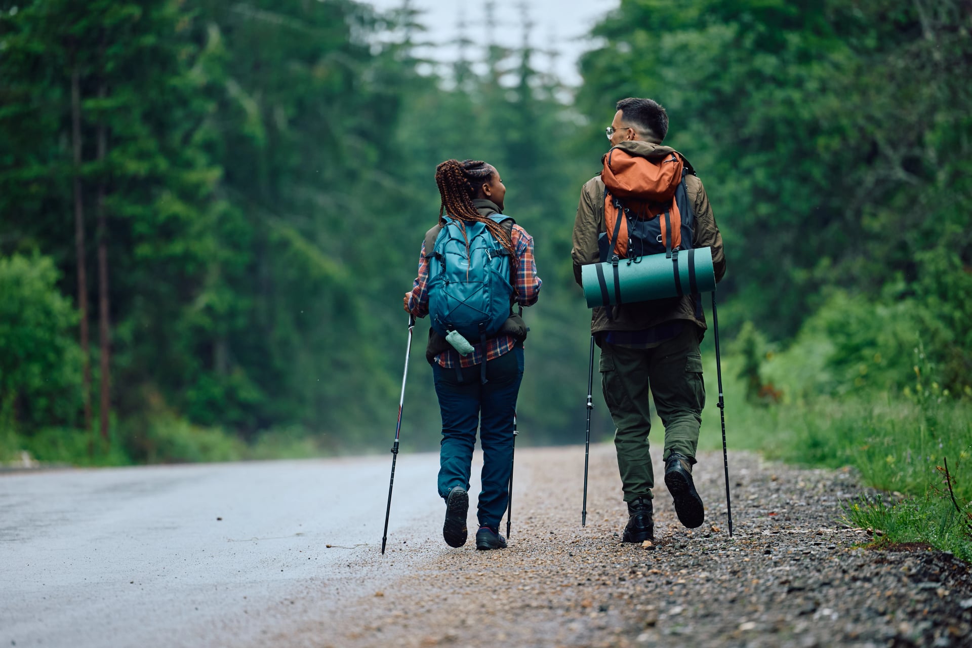 Rear view of backpackers walk by road in nature.